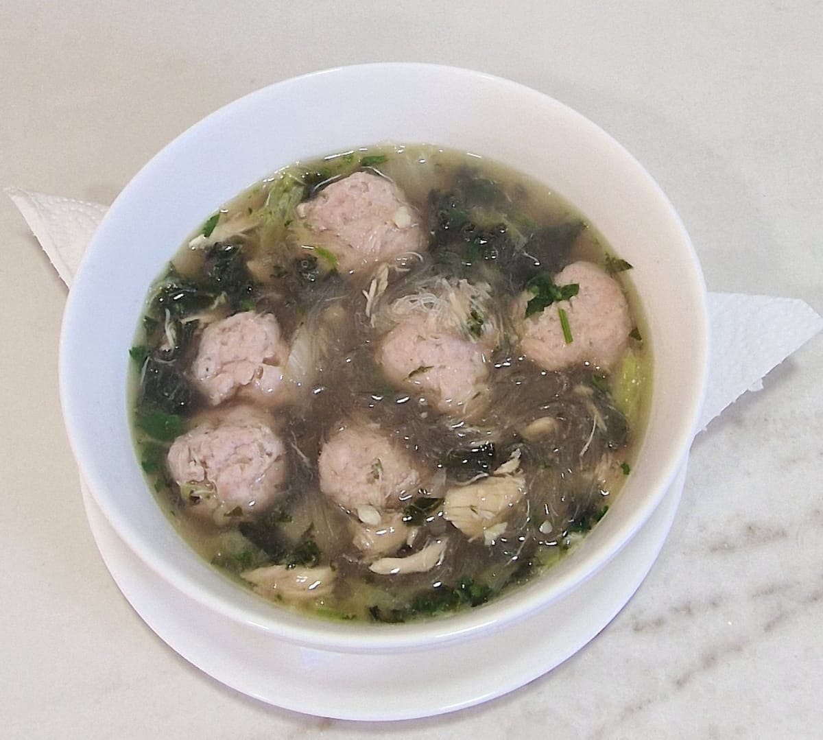 Chicken meatball soup with glass noodles and seasonal greens