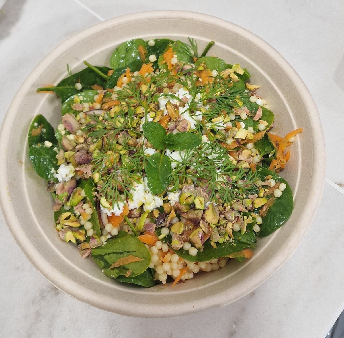 Pearl couscous salad, dates, feta, roasted pistachios and green herbs